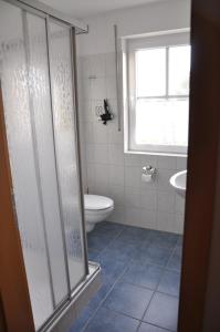 a bathroom with a shower and a toilet and a window at Ferienhaus Baltrumkieker Links in Neßmersiel +22 photos