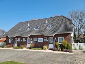 a red brick house with a black roof at Ferienhaus Backbord im Bootshaus in Neßmersiel