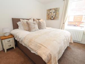 a bedroom with a large bed with white sheets and a window at Flat 2 in Prestatyn