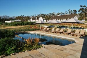 einen Pool mit Liegestühlen und Sonnenschirmen in einem Resort in der Unterkunft Rijk's Wine Estate & Hotel in Tulbagh