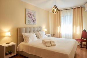 um quarto com uma cama branca e uma pintura de flores cor-de-rosa em Cantinho D'Os Reais no Pinhão