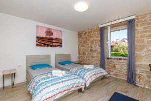 two beds in a room with a brick wall at Pepe&Lynn in Višnjan +6 photos