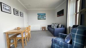 a living room with a table and a blue couch at The Steamboat - A Flat with Amazing Harbour Views in Wick