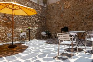 eine Terrasse mit Tischen, Stühlen und einem Sonnenschirm in der Unterkunft Balhondo Open Village in Puebla de Alcocer