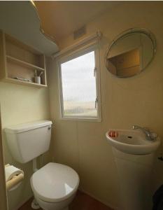 a bathroom with a toilet and a sink and a window at Steeple Bay F79 in Steeple