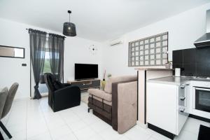 a kitchen and living room with a couch and a television at SUNSET APARTMENTS RABAC in Rabac
