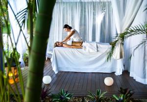 a woman sitting on a bed with a woman laying on it at PortoBay Búzios in Búzios