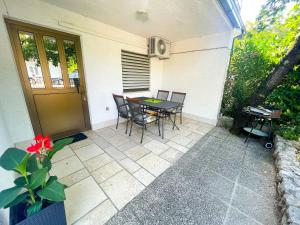 une terrasse avec une table et des chaises à côté d'une maison dans l'établissement Apartmani Irena, à Jadranovo