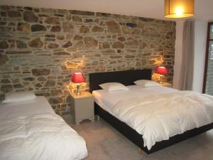 1 dormitorio con 2 camas y pared de piedra en Gite Kooa, en Theux