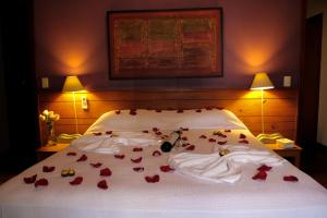 a bed with red rose petals laying on it at Pousada Do Capitão in Florianópolis