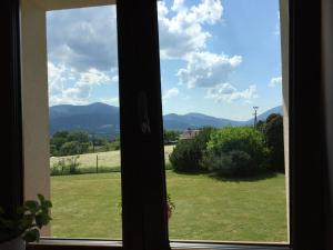 a window with a view of a field and mountains at Penzion Na Vyhlídce in Frýdlant nad Ostravicí