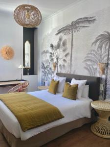 - une chambre avec un grand lit orné d'une fresque murale en palmier dans l'établissement Hôtel La Résidence, à Narbonne