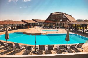 a large swimming pool with chairs and an umbrella at Guararema Parque Hotel in Guararema
