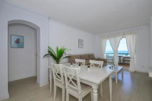 une salle à manger blanche avec une table et des chaises blanches dans l'établissement Barrosa Frente al Mar, à Chiclana de la Frontera