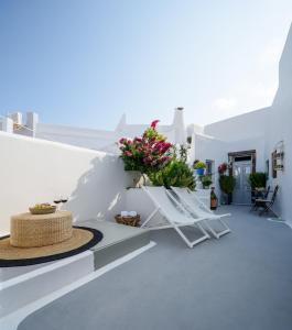 a white balcony with flowers on a white wall at Betty's Home Santorini in Karterados