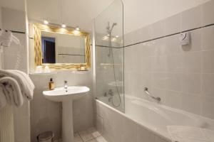 La salle de bains blanche est pourvue d'un lavabo et d'une douche. dans l'établissement Hôtel La Résidence, à Narbonne