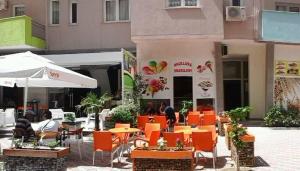 a restaurant with orange tables and chairs in front of a building at Comfortable apartment in Shëngjin