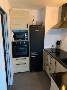a kitchen with a black refrigerator and a microwave at Appartement vue sur mer, 30m de la plage in Lacanau-Océan