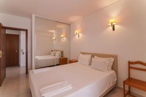 a bedroom with a large white bed and a mirror at Oura 9ºa in Armação de Pêra