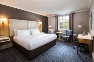a hotel room with a bed and a desk at Oulton Hall Hotel, Spa & Golf Resort in Leeds
