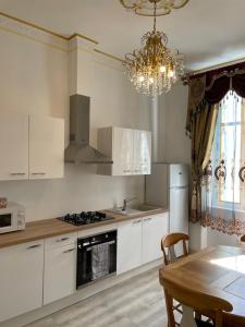 a kitchen with white cabinets and a table and a chandelier at Studio familial Maison de L'église du Couvent in Narbonne