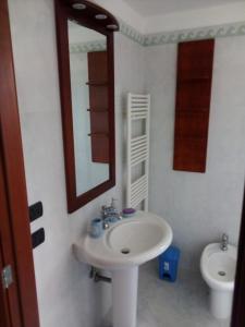 ein Badezimmer mit einem Waschbecken, einem Spiegel und einem WC in der Unterkunft Attico Matine in Specchia