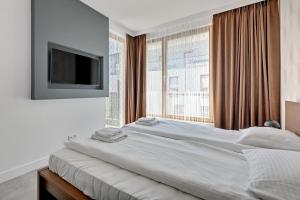 a white bedroom with a large bed and a large window at Dom & House - Apartments Nadmorski Park in Gdańsk