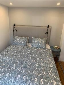ein Bett mit einer blauen und weißen Bettdecke und zwei Kissen in der Unterkunft Nyrenoverat källarlägenhet in Ljungskile