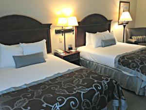 um quarto de hotel com duas camas e uma cadeira em Wingate by Wyndham Charleston Southern University em Charleston