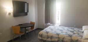 1 dormitorio con cama, mesa y TV en Motel 6 Mobile, AL - Airport Blvd, en Mobile