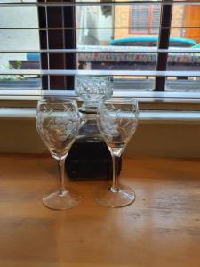 two wine glasses sitting on a table near a window at Happy colourful cottage in Johannesburg