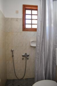 a bathroom with a shower with a toilet and a window at Village Twins in Ios Chora