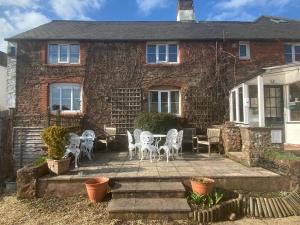 een stenen huis met een patio met stoelen en tafels bij The Martlet Inn in Wellington