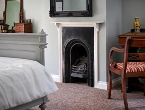 a room with a fireplace with a chair and a mirror at The Martlet Inn in Wellington