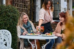 tres mujeres sentadas alrededor de una mesa comiendo comida en The Martlet Inn, en Wellington