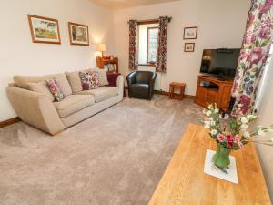a living room with a couch and a table and a tv at 1 Netherbeck Barn in Carnforth
