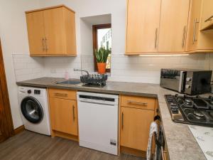 - une cuisine avec des placards en bois et un lave-vaisselle blanc dans l'établissement 1 Netherbeck Barn, à Carnforth
