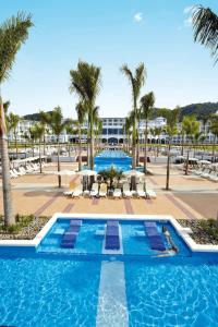 a swimming pool with palm trees and a resort at Riu Palace Costa Rica - All Inclusive in Coco