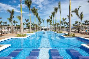 a swimming pool with palm trees in a resort at Riu Palace Costa Rica - All Inclusive in Coco
