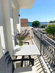 een tafel op een balkon met een vaas met bloemen bij Apartments Dalmatino in Vodice