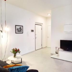 a white living room with a couch and a tv at Athena Design Apartment in Siracusa