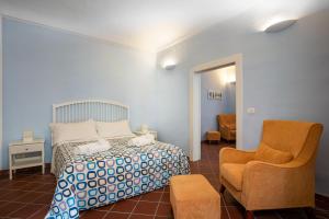 um quarto com uma cama e uma cadeira em I Tre Balconi di Via Roma Apartment em Siracusa