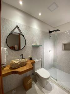 ein Badezimmer mit Toilette, Waschbecken und Spiegel in der Unterkunft Azul de Milagres in São Miguel dos Milagres