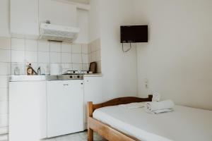 a small white kitchen with a bed in a room at Filippos Rooms Afissos in Afissos
