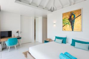 a bedroom with a white bed and a blue chair at Villa King Gustaf in Gustavia