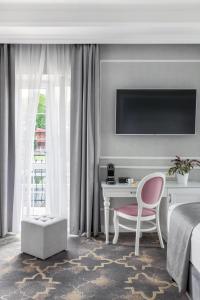 a hotel room with a bed and a desk and a tv at Merci Boutique Hotel in Kraków