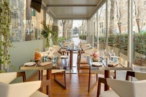 a restaurant with tables and chairs and windows at Meliá Genova in Genova