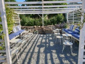 un patio con sillas y mesas bajo una pérgola blanca en Marsjö Gård Bo & Yoga vandrarhem en Borgholm