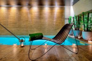 einen Stuhl mit einem grünen Kissen darauf vor einem Pool in der Unterkunft Meliá Genova in Genua