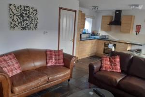 un salon avec deux canapés en cuir et une cuisine dans l'établissement The Stable, à Aberystwyth